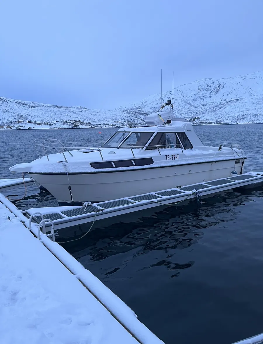 Fiskebåt ved kai i snødekt fjord