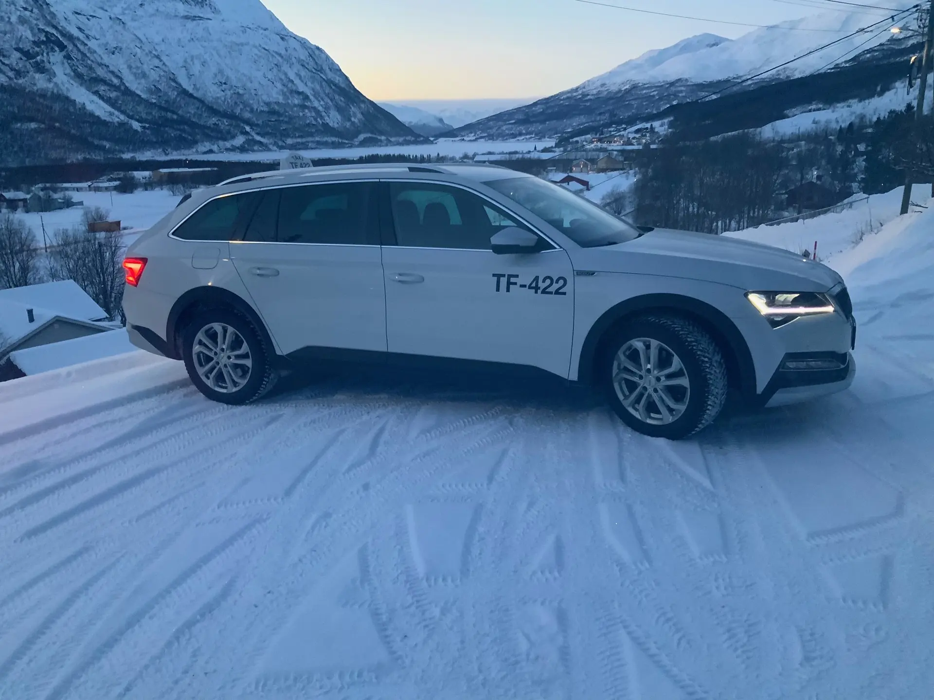 Hvit taxi i snølandskap med fjell i Nord-Troms